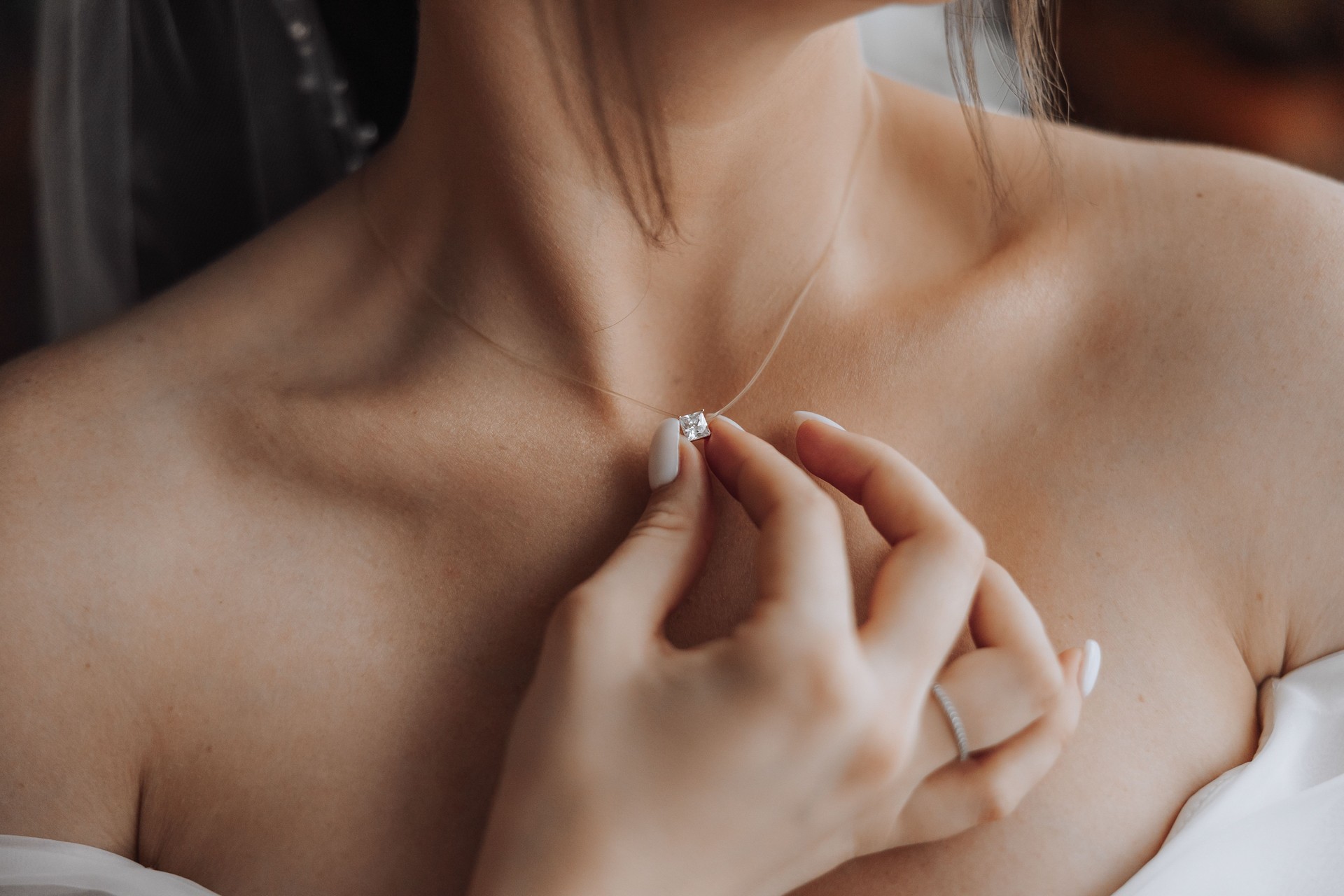 A woman is wearing a necklace and holding it up to her neck